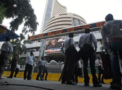 People look at a large screen displaying India's Finance Minister Mukherjee announcing the federal budget on the facade of BSE building in Mumbai (Arko Datta / Courtesy Reuters).