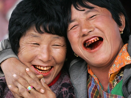 Women, their teeth red from chewing betel nuts, laugh at a vegetable market in Bhutanese capital Thimpu, October 23, 2006 (Gopal Chitrakar/Courtesy Reuters).