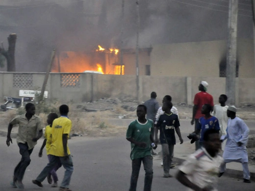 Smoke rises from the police headquarters as people run for safety after Boko Haram bomb blasts in Nigeria's northern city of Kano January 20, 2012.