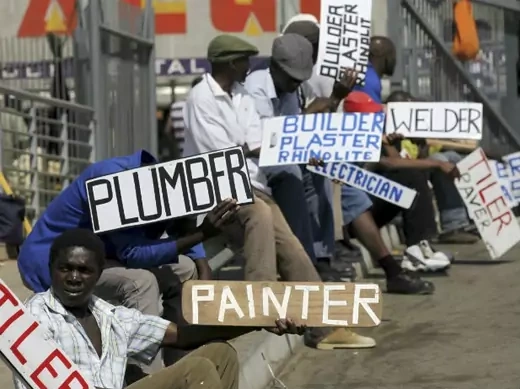 Men hold placards offering temporary employment services in Glenvista, south of Johannesburg, October 7, 2010.