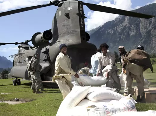 Pakistani men throw a bag of flour onto a pile out the back of a U.S. Army Chinook helicopter in Khyber Pakhtunkhwa province