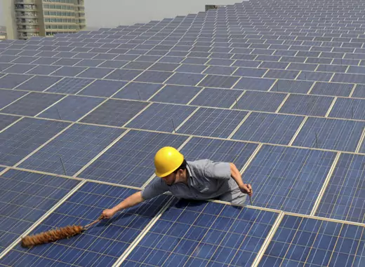 A worker cleans solar panels on a rooftop in Zhejiang Province, China (Stringer/Courtesy Reuters). 