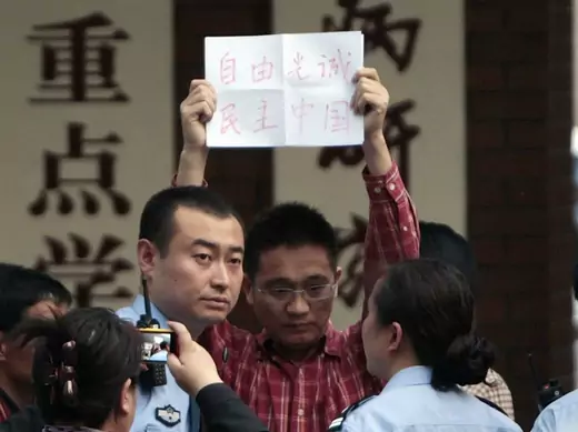 A supporter of Chen Guangcheng holds up a piece of paper reading, "Freedom, Guangcheng, Democracy, China", as he is being taken away by police officers at Chaoyang Hospital in Beijing, where blind activist Chen Guangcheng was reported to be staying on May 2, 2012.