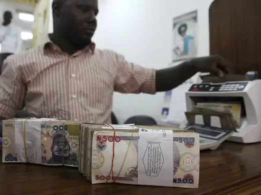 A money dealer counts the Nigerian naira on a machine in his office in the commercial capital of Lagos, January 13, 2009.