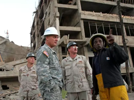 Three U.S. officers of the U.S. joint military effort from the Combined Joint Task Force (CJTF)-Djibouti are introduced to the site by a Kenyan engineer (R) after they arrived at the scene of a collapsed building in Nairobi, Kenya January 24, 2006.