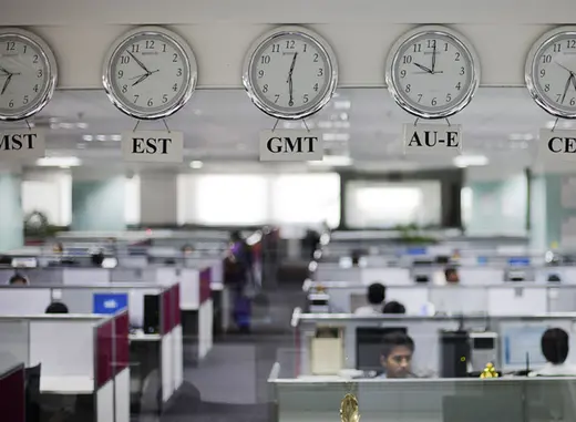 Workers are pictured beneath clocks displaying time zones at an outsourcing center in Bangalore (Vivek Prakash/Courtesy Reuters).
