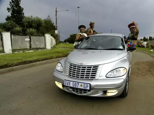 Township residents pose on a luxury car in Soweto's Thokoza Park March 25, 2006.