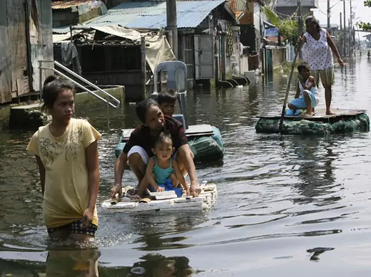 Residents use an improvised raft, made of styrofoam, to cross floodwaters at Dampalit town in Malabon city