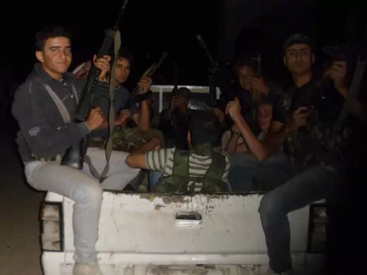 Members of the Free Syrian Army holding weapons sit at the back of a truck in Aleppo