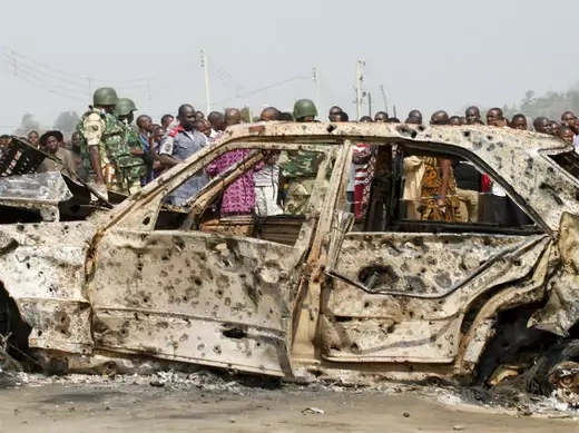 A crowd gathers near a car damaged by an explosion at St. Theresa Catholic Church at Madalla, Suleja, just outside Nigeria's capital Abuja, December 25, 2011.
