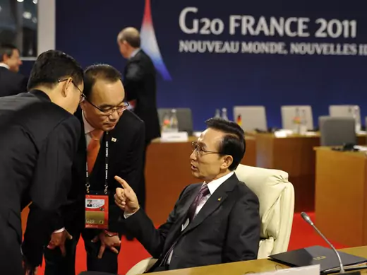 South Korea's President Lee Myung-bak speaks to members of his delegation while awaiting the start of a meeting on the second day of the G20 Summit in Cannes