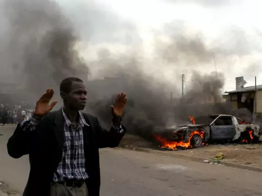 A man walks past a burning car in Oshodi, Lagos south west Nigeria May 24, 2005.
