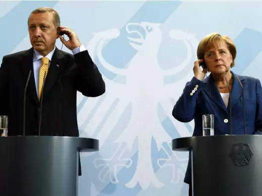 Turkey's PM Erdogan and German Chancellor Merkel adjust their earphones for the translations as they address a news conference following their bilateral talks in Berlin (Fabrizio Bensch/Courtesy Reuters)