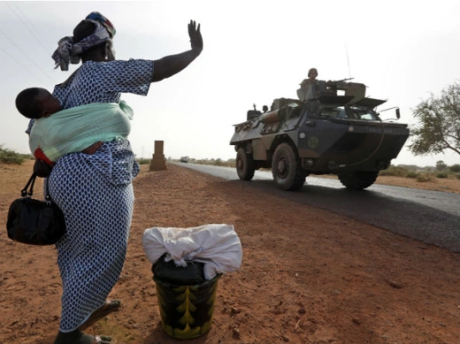 A woman waves to French soldiers heading toward the recently liberated town of Diabaly 24/01/2013.