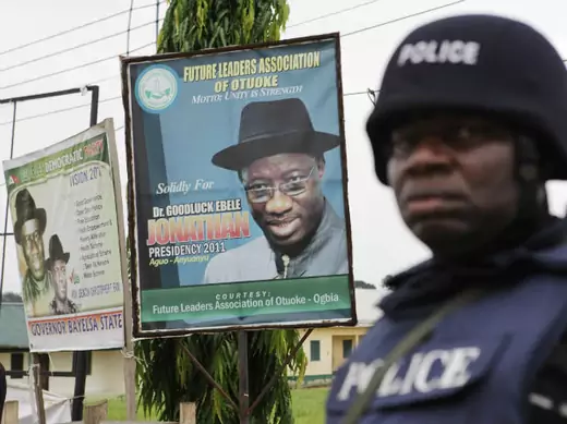  An armed police officer in riot gear stands guard in front of a poster of Nigerian incumbent President Goodluck Jonathan in Otuoke 16/04/2011.