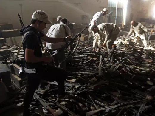 Anti-Gaddafi fighters salvage weapons from a pro-Gaddafi loyalist weapons and ammunition compound in a village near Sirte
