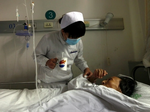 A nurse gives an infected patient medicine as she lies in her bed at the HIV/AIDS ward of Beijing YouAn Hospital on December 1, 2011.