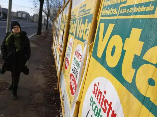 A woman walks past election posters in Rome (Tony Gentile/Courtesy Reuters). 