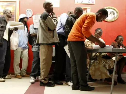 Zimbabweans recieve forms as they queue to apply for residence and study permits outside the Home Affairs office in Cape Town, December 31, 2010. 