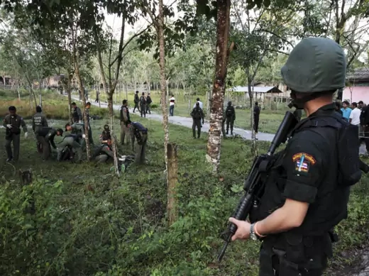 Security personnel investigate around bodies of insurgents at the site of an attack on an army base in the troubled southern province of Narathiwat February 13, 2013.