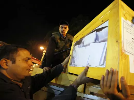 Egyptian electoral workers carry ballot box at a center for vote counting during a previous parliamentary election (El-Ghany/Courtesy Reuters).