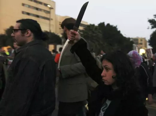 A woman raises a knife against Egyptian president Mohammed Morsi and members of the Brotherhood during a march against sexual harassment and violence against women in Cairo February 6, 2013 (Dalsh/Courtesy Reuters).. 