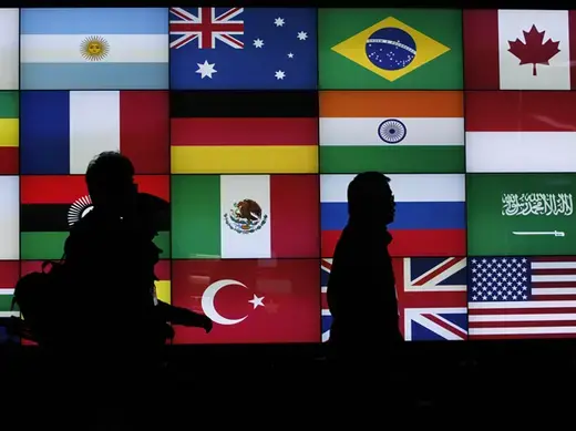 Media workers walk past a screen showing flags of the participating countries during the G20 summit in Seoul, South Korea (Jo Yon-Hak/Courtesy Reuters).