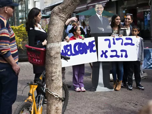 An Israeli family holds welcome signs in Hebrew and English during an event organized by the U.S. embassy in Tel Aviv on March 1, 2013 (Nir Elias/Courtesy Reuters).