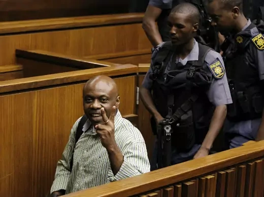 Nigerian militant leader Henry Okah (L) gestures as he is escorted by police after his sentencing was postponed at a Johannesburg court February 28, 2013.