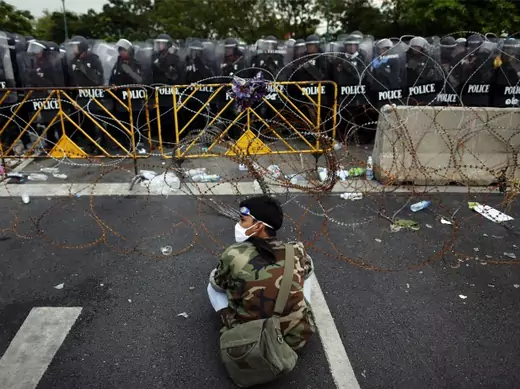 An anti-government protester sits in front of riot police near the Government house in Bangkok on November 24, 2012.