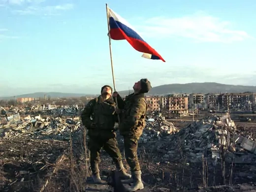 Russian soldiers stand with a raised flag after an operation in the Chechen capital Grozny on February 27, 2000 (Courtesy Reuters).