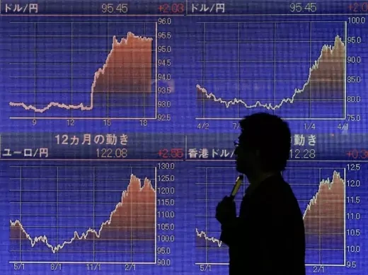 A man walks past an electronic board showing the graphs of exchange rates between the Japanese yen, the U.S. dollar and Euro outside a brokerage in Tokyo on April 4, 2013. (Courtesy Reuters/Yuya Shino)