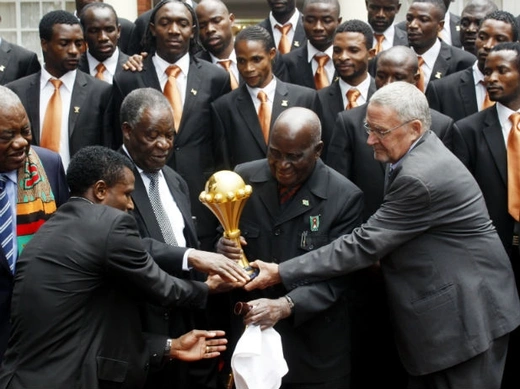 Zambia President Michael Chilufya Sata (3rd L) touches the African Nations Cup trophy with founding President Kenneth Kaunda (2nd R), Vice President Guy Scott (R) as members of the Zambia soccer team (back) and former President Rupiah Band (L) look on, during a ceremony at the State House in Lusaka February 14, 2012
