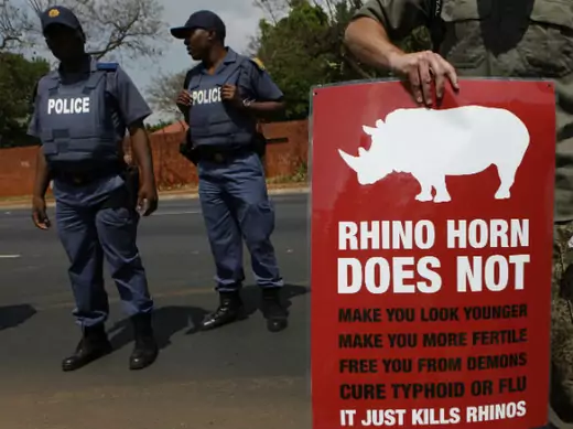 Policeman look on as a protester carries a placard calling for an end to rhino poaching, which threatens the survival of rhino species, outside the Chinese embassy in Pretoria September 22, 2011. (Siphiwe Sibeko/Courtesy Reuters)