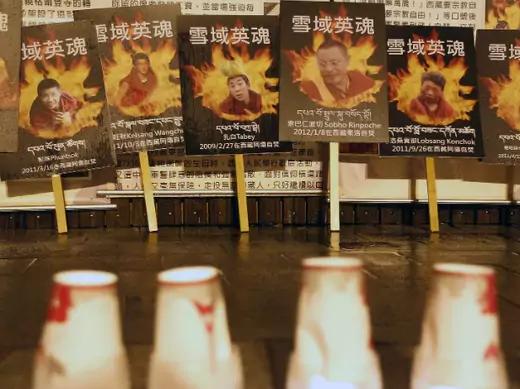 Portraits of Tibetans who killed themselves in self-immolation are seen behind candles in a candlelight vigil.
