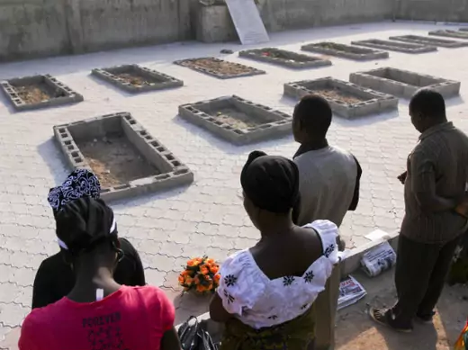 People pray near the graves of victims of a suicide bomb attack during a memorial service at St. Theresa's Church in Madalla, on the outskirts of Nigeria's capital Abuja, December 23, 2012.
