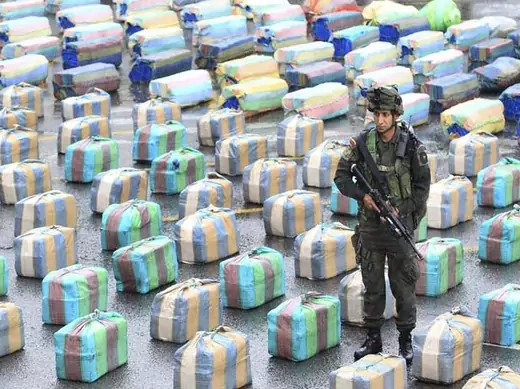 A Colombian police officer stands guard near packs of confiscated marijuana in Cali