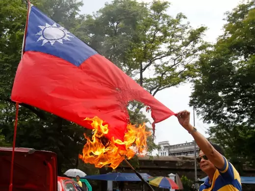 Former police officer Abner Afuang burns a replica of Taiwan's national flag as he protests against the mistreatment of Filipinos working overseas, along a main street of Manila on May 17, 2013. (Courtesy Reuters/Romeo Ranoco)
