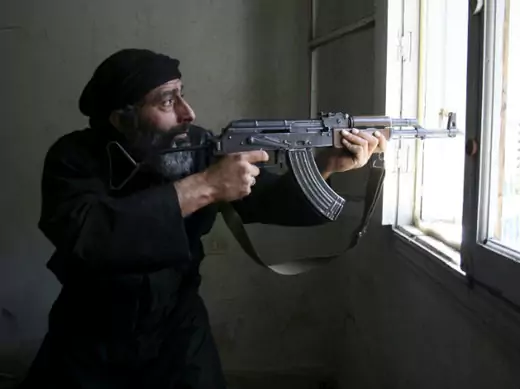 A Free Syrian Army fighter aims his AK-47 rifle through a window in Aleppo's Salaheddine neighbourhood (Hretani/Courtesy Reuters).