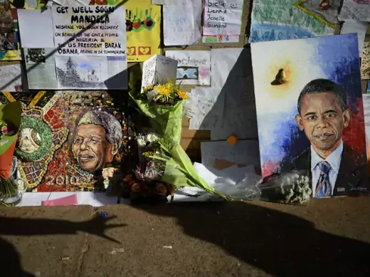 Wellwishers cast shadows in front of portraits of Nelson Mandela (L) and U.S. President Barack Obama outside the Medi-Clinic Heart Hospital, where the ailing former South African President is being treated, in Pretoria June 28, 2013.