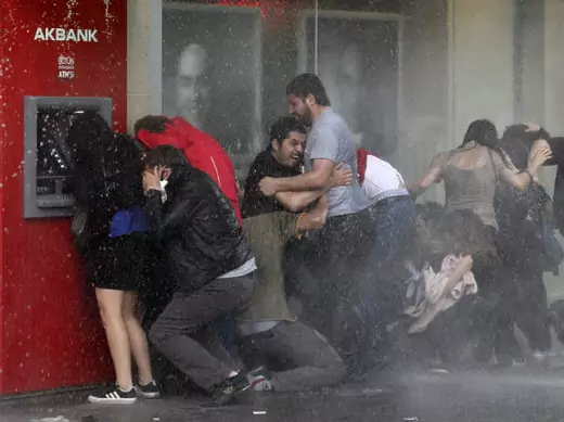Anti-government protesters try to protect themselves from a water cannon as riot police disperse them during a protest in Ankara June 5, 2013 (Bektas/Courtesy Reuters)..