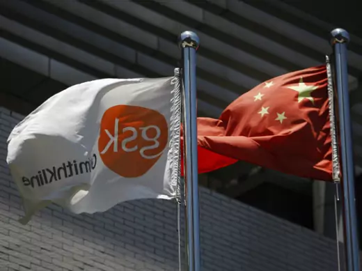 A flag (L) bearing the logo of GlaxoSmithKline (GSK) flutters next to a Chinese national flag outside a GlaxoSmithKline office building in Shanghai on July 12, 2013.