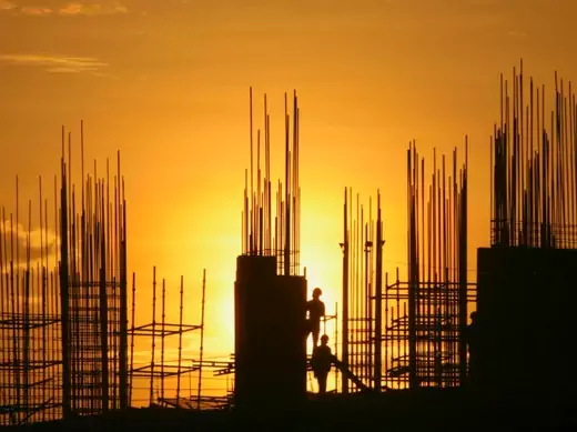 Labourers are silhouetted against the setting sun as they work at the construction site of a residential building in the southern Indian city of Hyderabad on October 5, 2012.