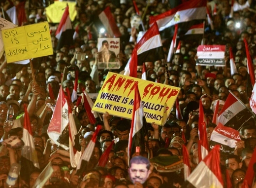 Members of the Muslim Brotherhood and supporters of deposed Egyptian President Mohamed Mursi wave Egyptian flags, signs and masks of him as they gather at the Rabaa Adawiya square, where they are camping, in Cairo on July 12, 2013. (Mohamed Abd El Ghany/Courtesy Reuters)