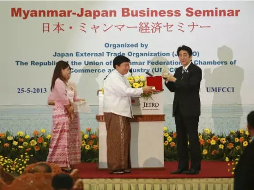 Japan's Prime Minister Shinzo Abe accepts a gift from Win Aung, the chairman of the Union of Myanmar Federation of Chambers of Commerce and Industry (UMFCCI), at a Myanmar-Japan business seminar at the UMFCCI premises in Yangon on May 25, 2013.  (Stringer/ Courtesy Reuters) 