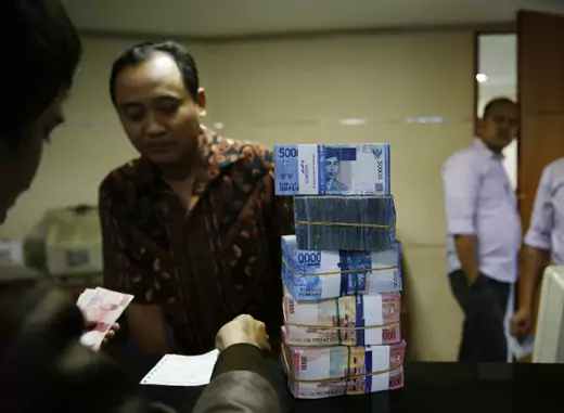 A money changer (facing camera) helps a customer convert Indonesian rupiah in Jakarta on August 20, 2013. Asian emerging market currencies extended losses on Tuesday, with the rupiah hitting a fresh four year low. (Beawiharta Beawiharta/Courtesy Reuters) 