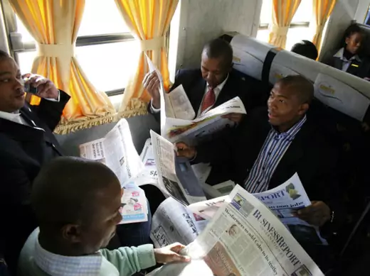 Passengers read newspapers on a business express train in Johannesburg December 11, 2008.