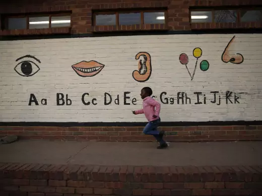 A child runs past a mural at a township school as the school prepares to wish former President Nelson Mandela happy birthday in Atteridgeville near Pretoria, July 18, 2013.