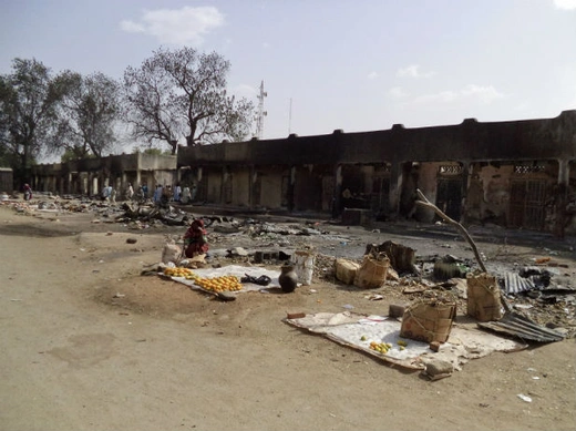 A woman sits amongst the burnt ruins of the Bama Market, which was destroyed by gunmen in last Thursday's attack, in Maiduguri, northeast Nigeria April 29, 2013.