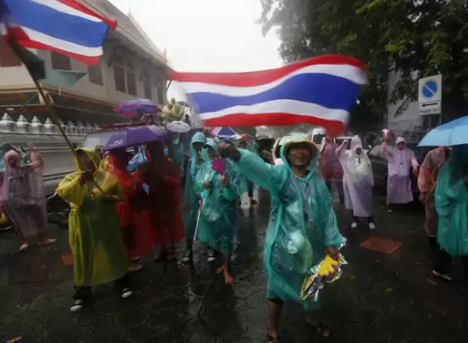 Anti-government protesters wave flags while standing in heavy rain outside the Interior Ministry in Bangkok on November 26, 2013. Nearly 3,000 flag-waving anti-government protesters massed in front of Thailand's Interior Ministry on Tuesday, a day after they stormed compounds of two other ministries. (Kerek Wongsa/Courtesy Reuters) 